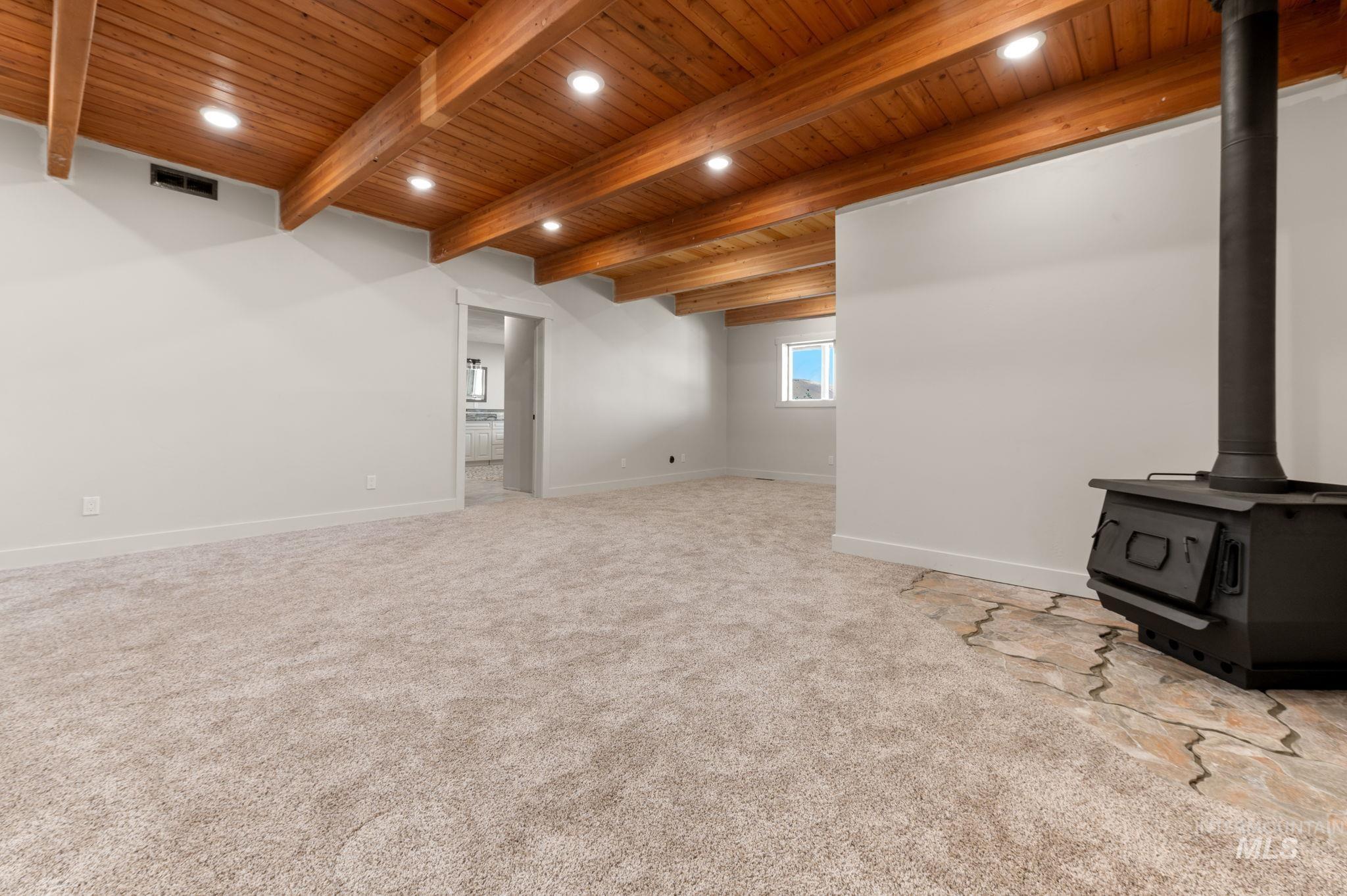Below grade area with a wood stove, wood ceiling, light carpet, and recessed lighting