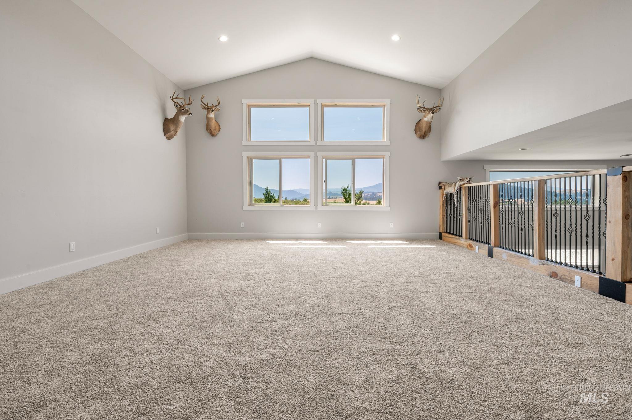 Unfurnished living room with carpet flooring and high vaulted ceiling