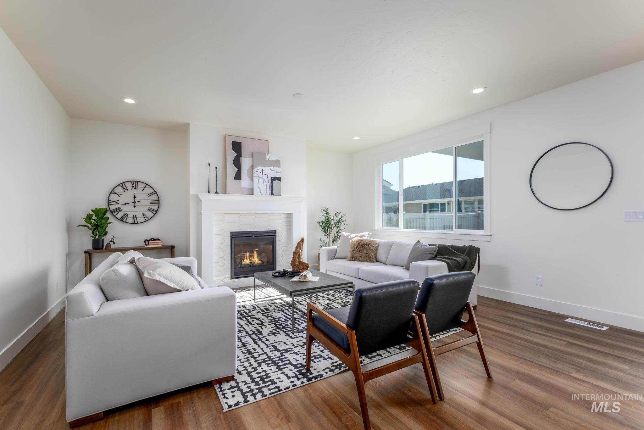 Living room with a glass covered fireplace, wood finished floors, and recessed lighting