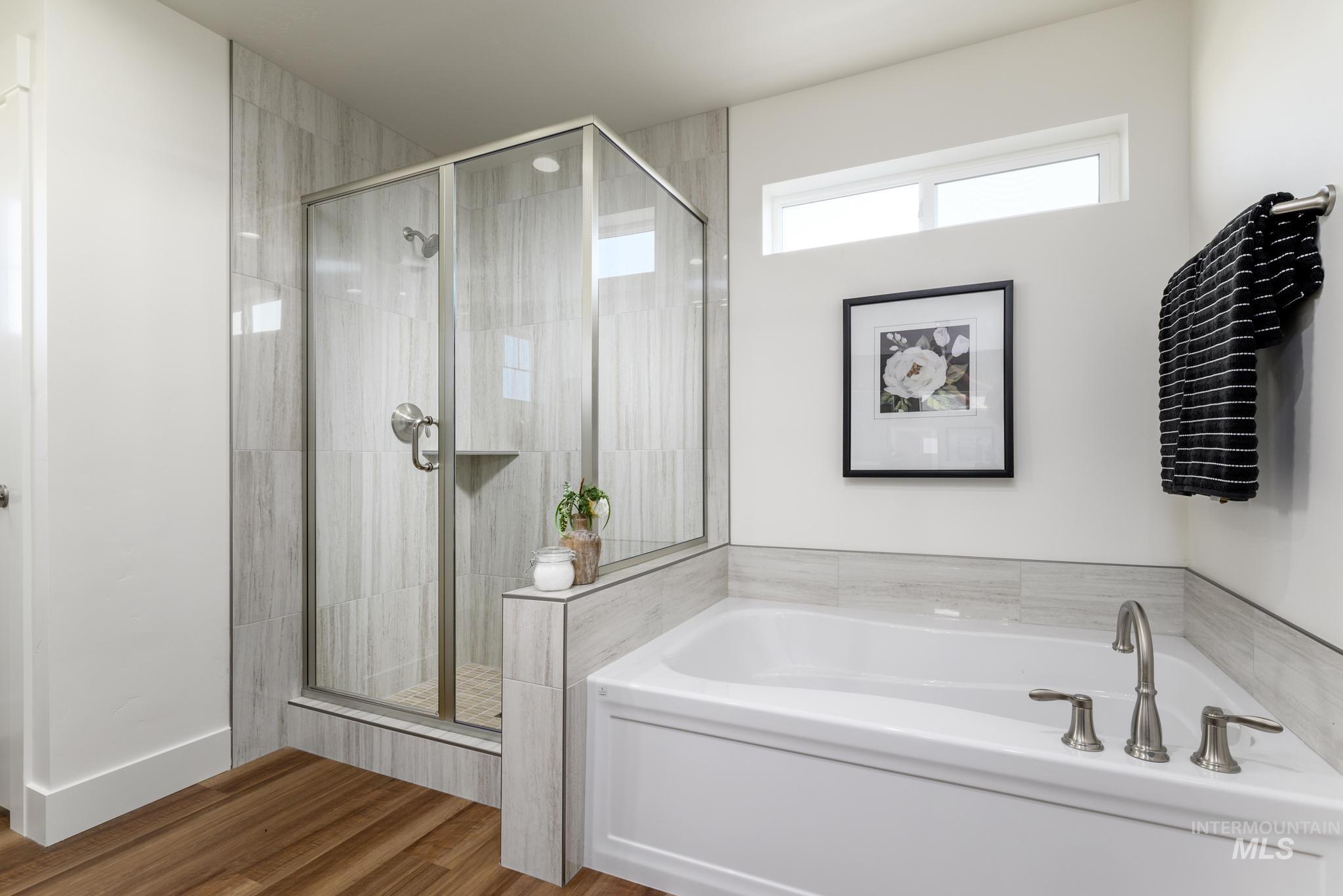 Full bathroom with a garden tub, wood finished floors, and a stall shower