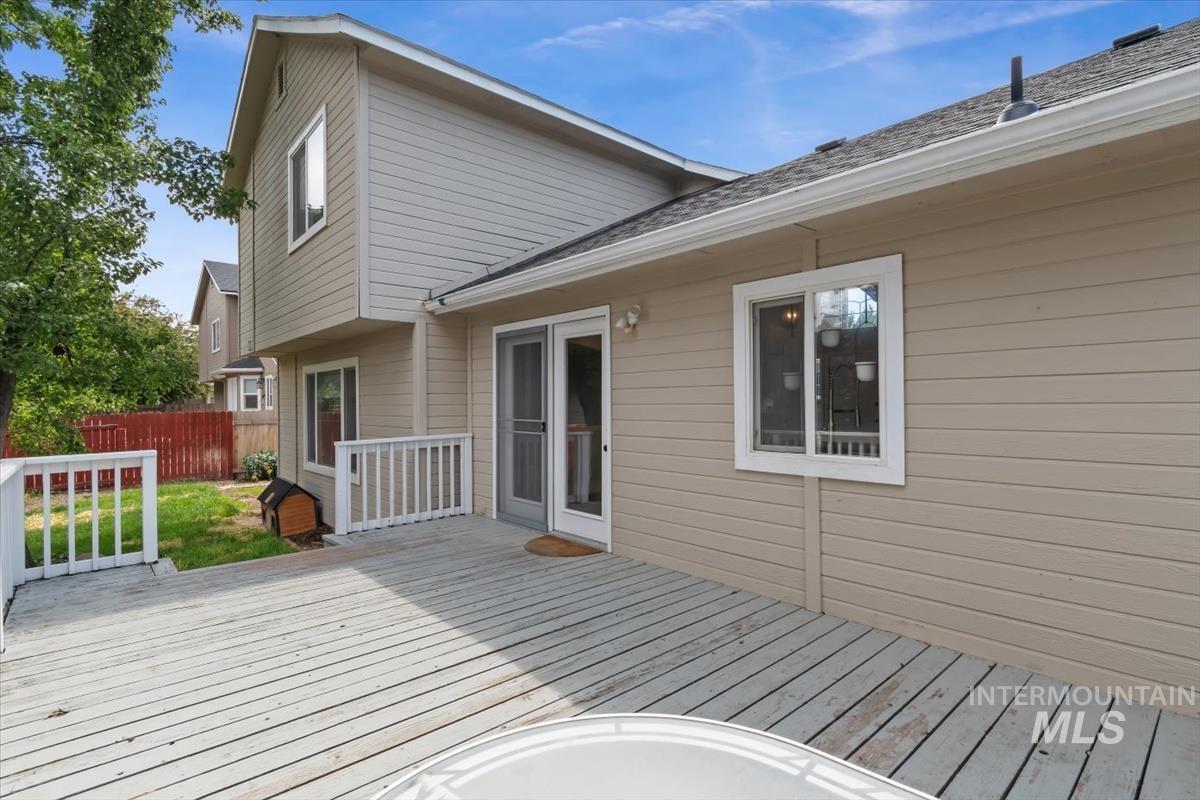 Expansive outdoor deck with white railing, featuring direct access to the interior via double glass patio doors