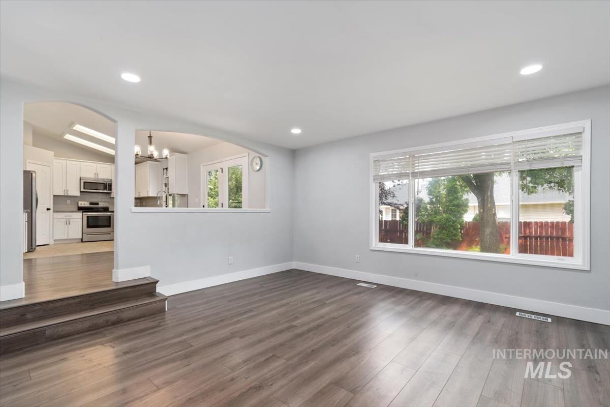 Living area featuring wood-finish flooring, recessed lighting, and a wide window with blinds