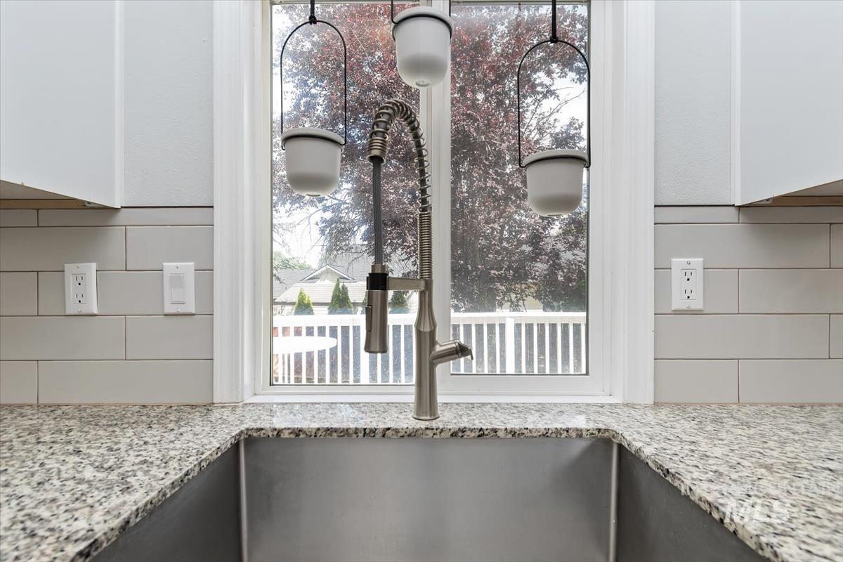 Stainless steel undermount sink with a brushed nickel pull-down faucet, set into a speckled granite countertop