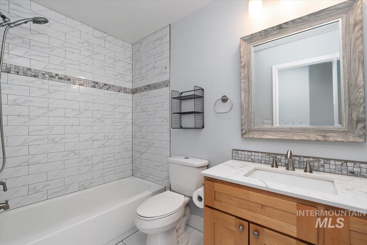 Bathroom with a built-in tub and shower featuring white subway tile surround with a decorative mosaic band