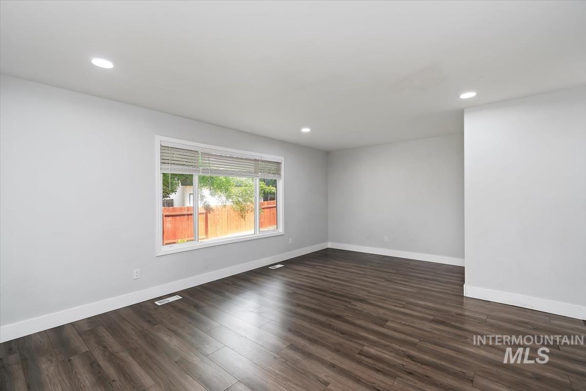 Spacious room with wood-finish flooring, recessed lighting, and a large window with blinds