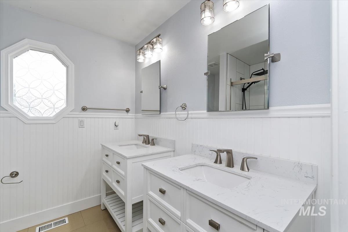 Dual vanity bathroom featuring white cabinetry with brushed nickel hardware, stone countertops, and undermount sinks