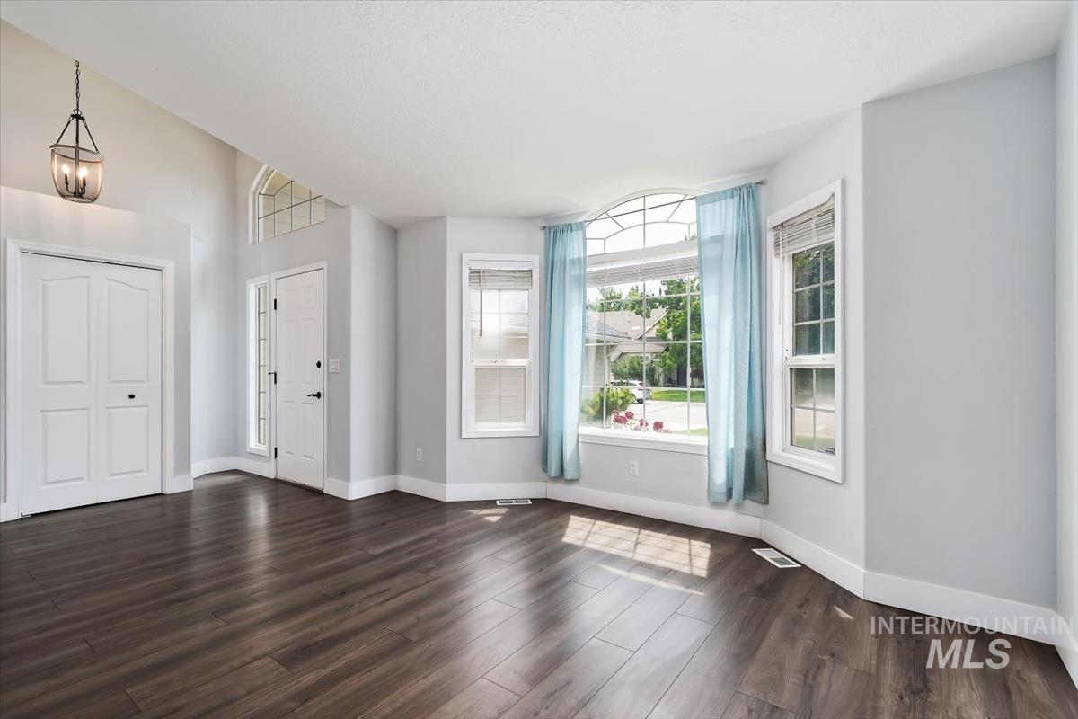 Spacious entry area featuring vaulted ceilings, dark wood-finish flooring, and crisp white trim