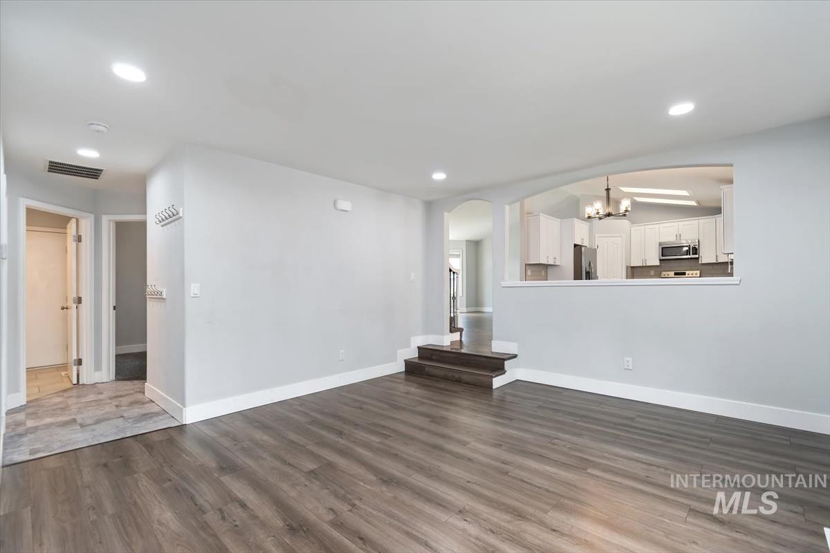 Spacious living area featuring wood-finish flooring, recessed lighting, and a partial wall opening to the kitchen