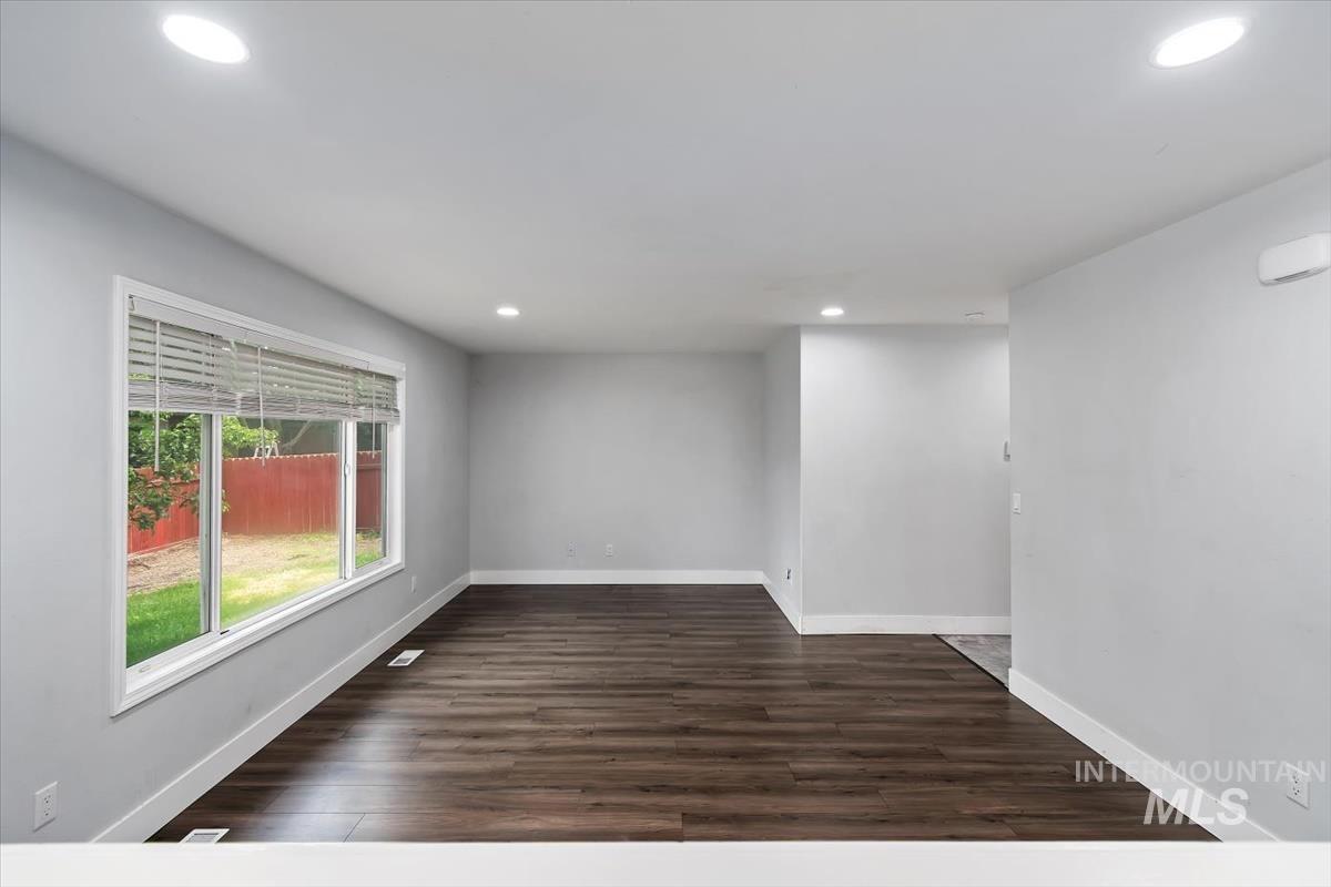 Spacious interior featuring wood-finish flooring, light grey walls, white trim, and recessed lighting
