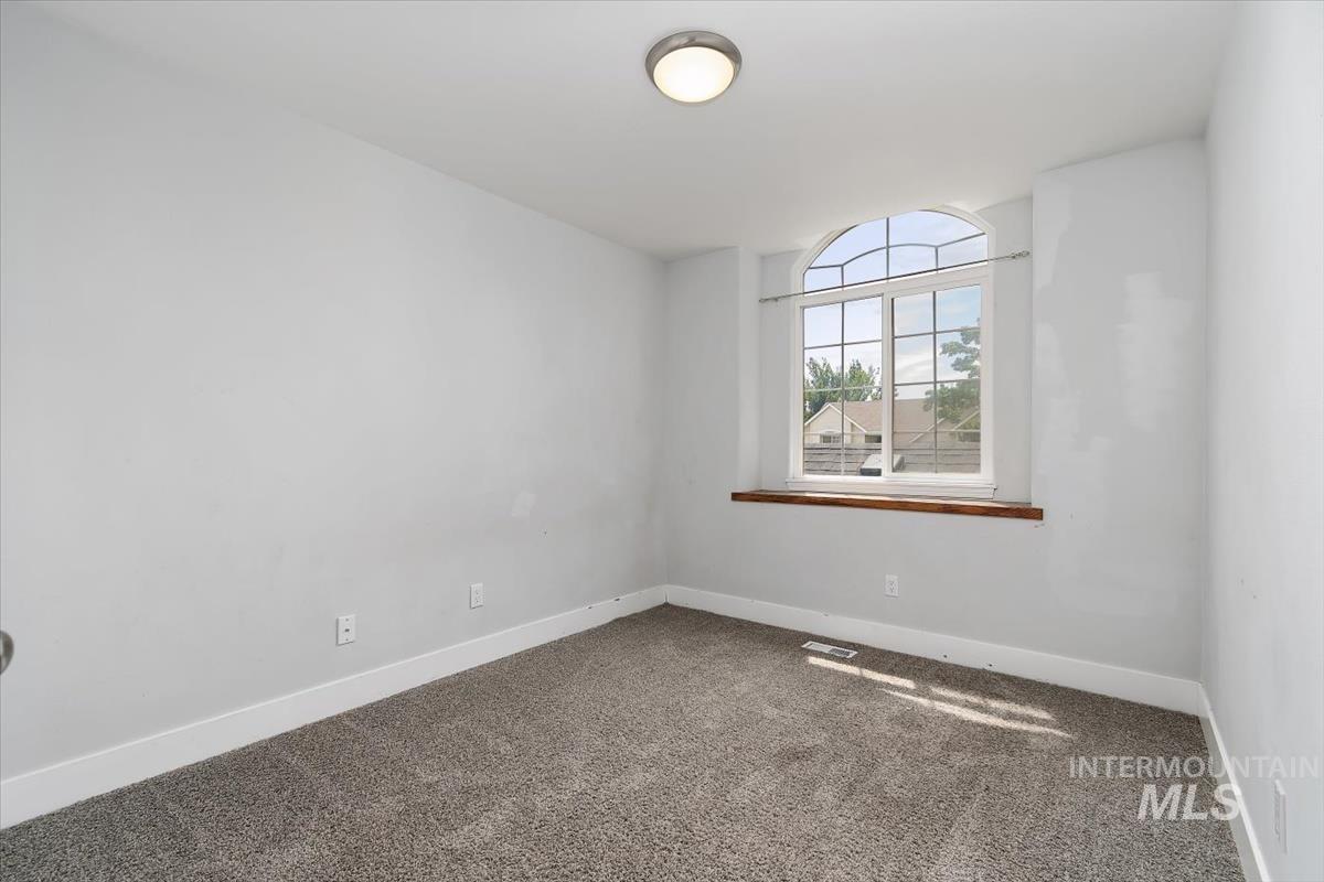 Room featuring an arched window, wood-finish window sill, gray carpeting, white walls, and a ceiling-mounted light fixture