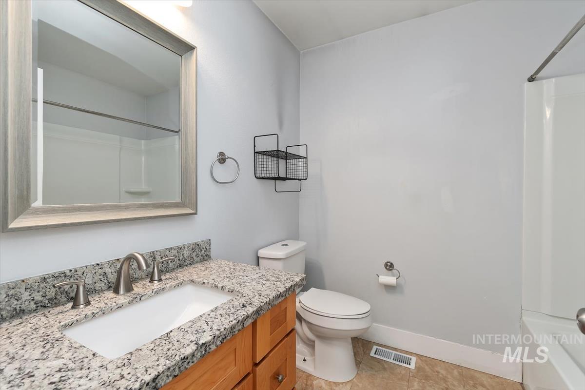 Bathroom featuring a light wood-finish vanity with a granite countertop, undermount sink, and brushed nickel faucet