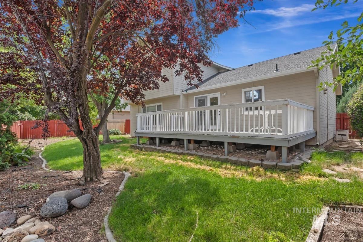 Rear exterior featuring a spacious wooden deck with white railings, a tan siding facade, and a dark shingle roof