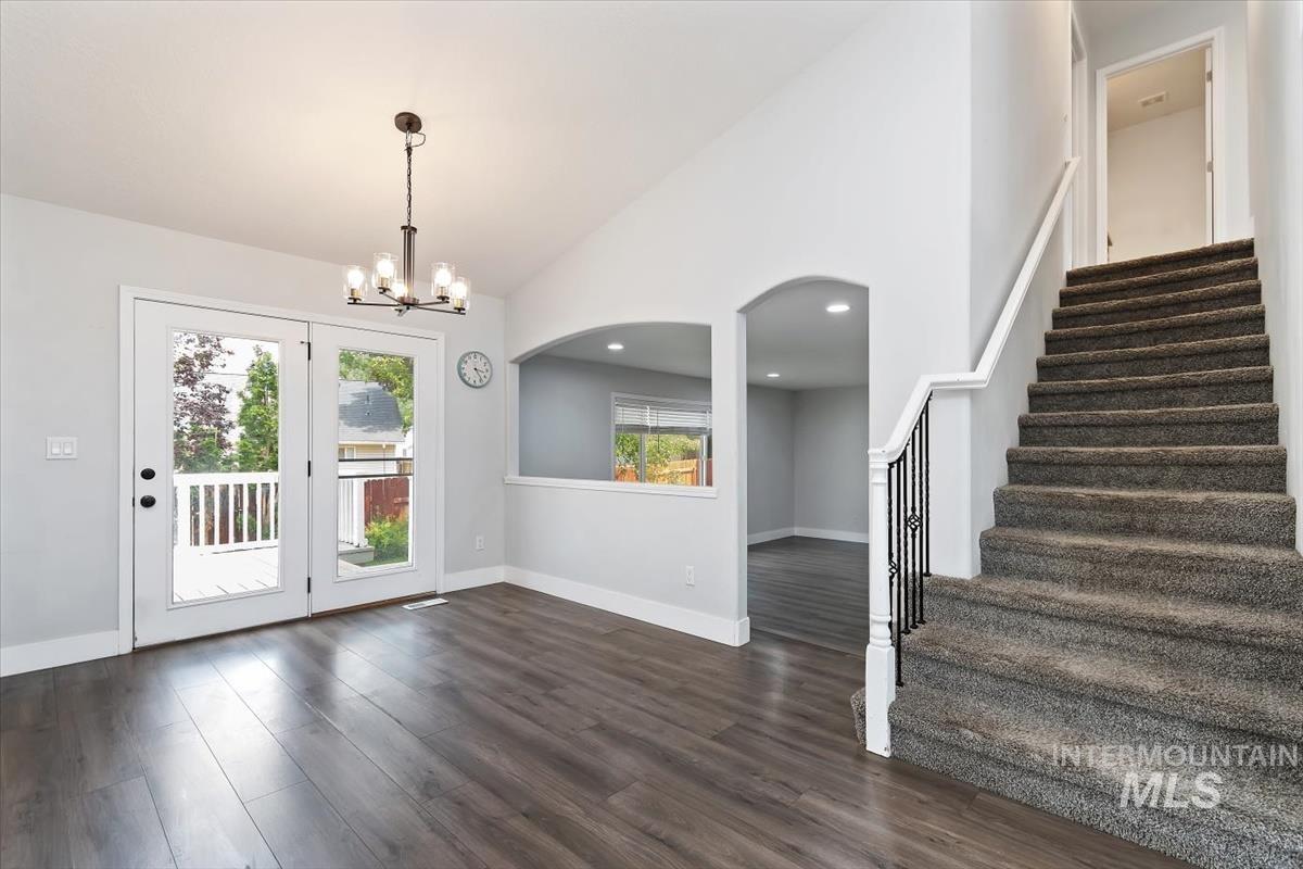 Spacious interior featuring wood-finish flooring, a vaulted ceiling, and a contemporary chandelier