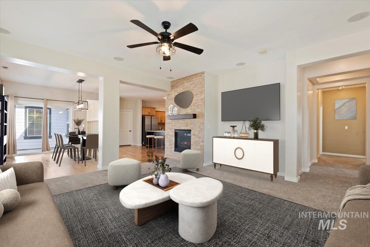 Living area with a fireplace, a ceiling fan, and carpet floors