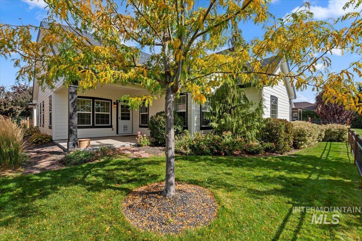 View of property hidden behind natural elements featuring a front lawn and a patio