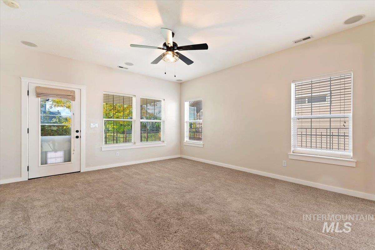 Unfurnished room with light colored carpet, plenty of natural light, and a ceiling fan