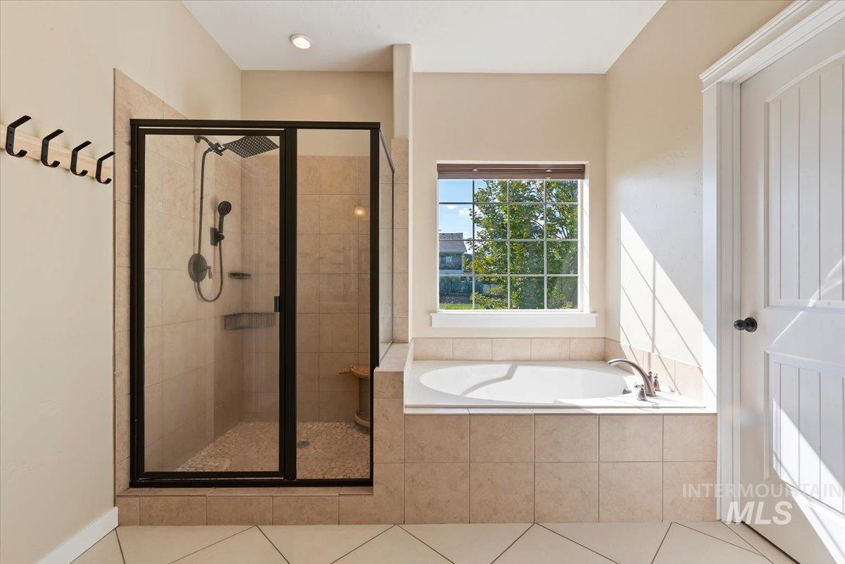 Bathroom with a stall shower, a garden tub, and tile patterned flooring