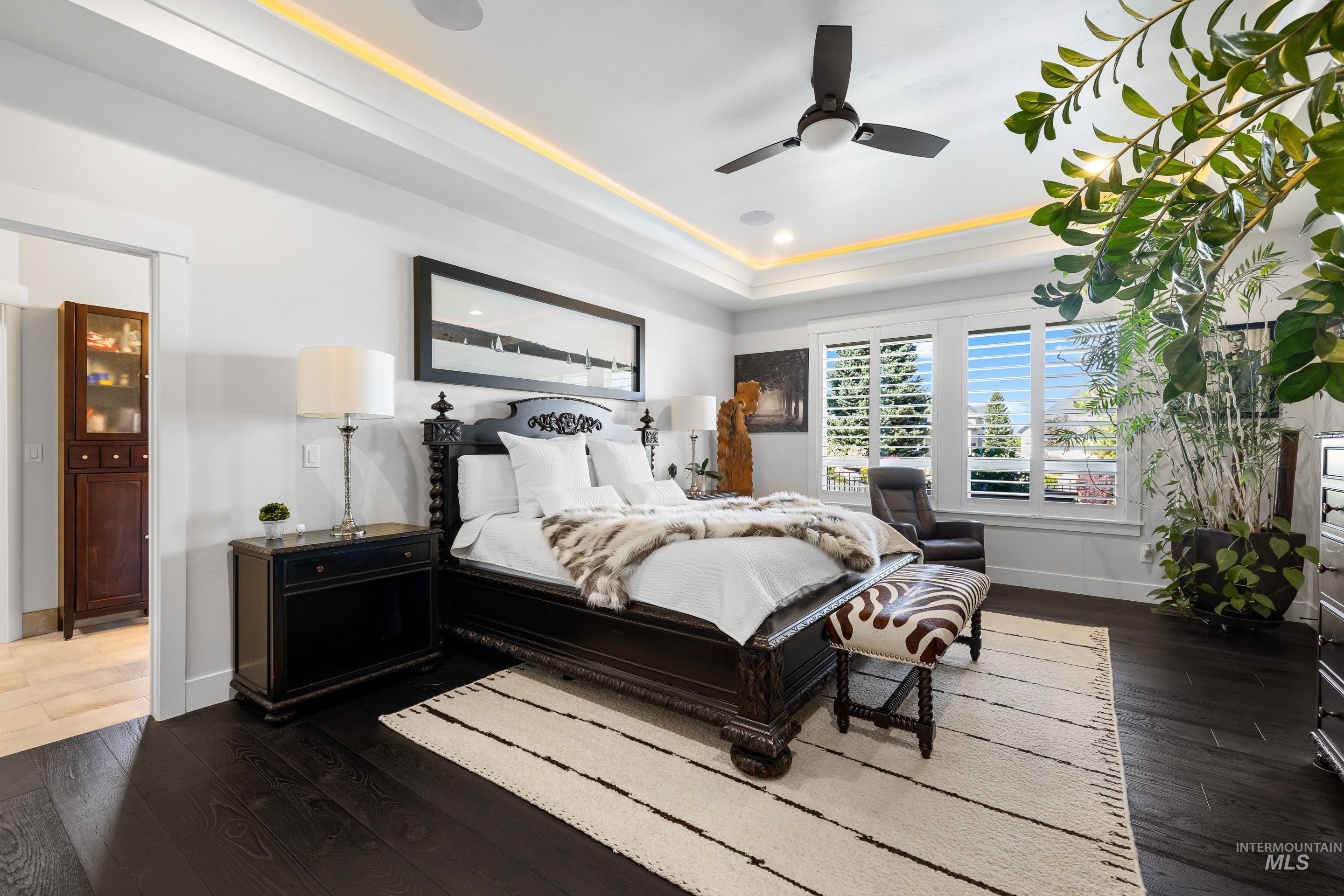 Bedroom with dark wood finished floors, a tray ceiling, and a ceiling fan