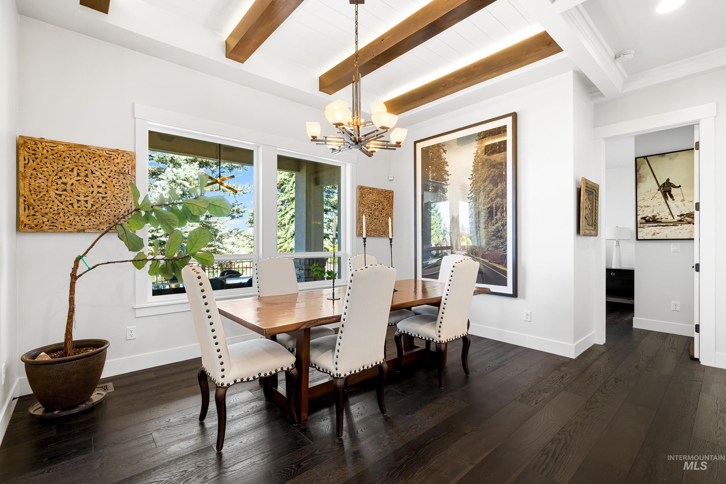Dining room with dark wood-style flooring, beam ceiling, and a chandelier
