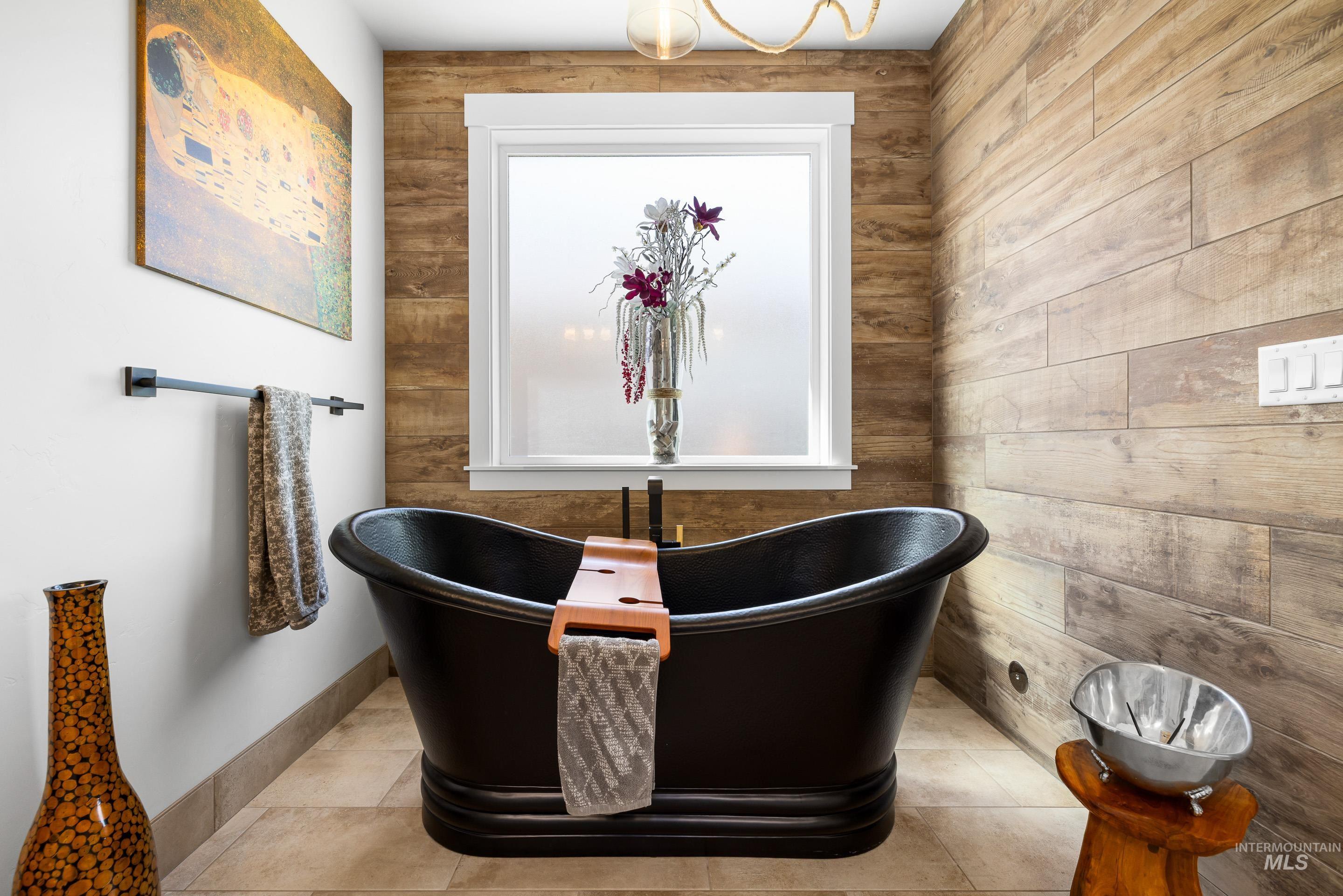Full bath featuring a freestanding tub, plenty of natural light, tile patterned flooring, and wood walls