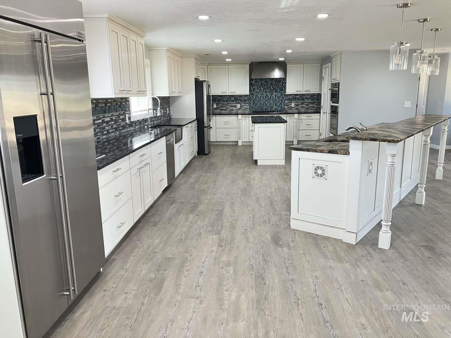 Kitchen with built in fridge, a center island, tasteful backsplash, recessed lighting, and decorative light fixtures