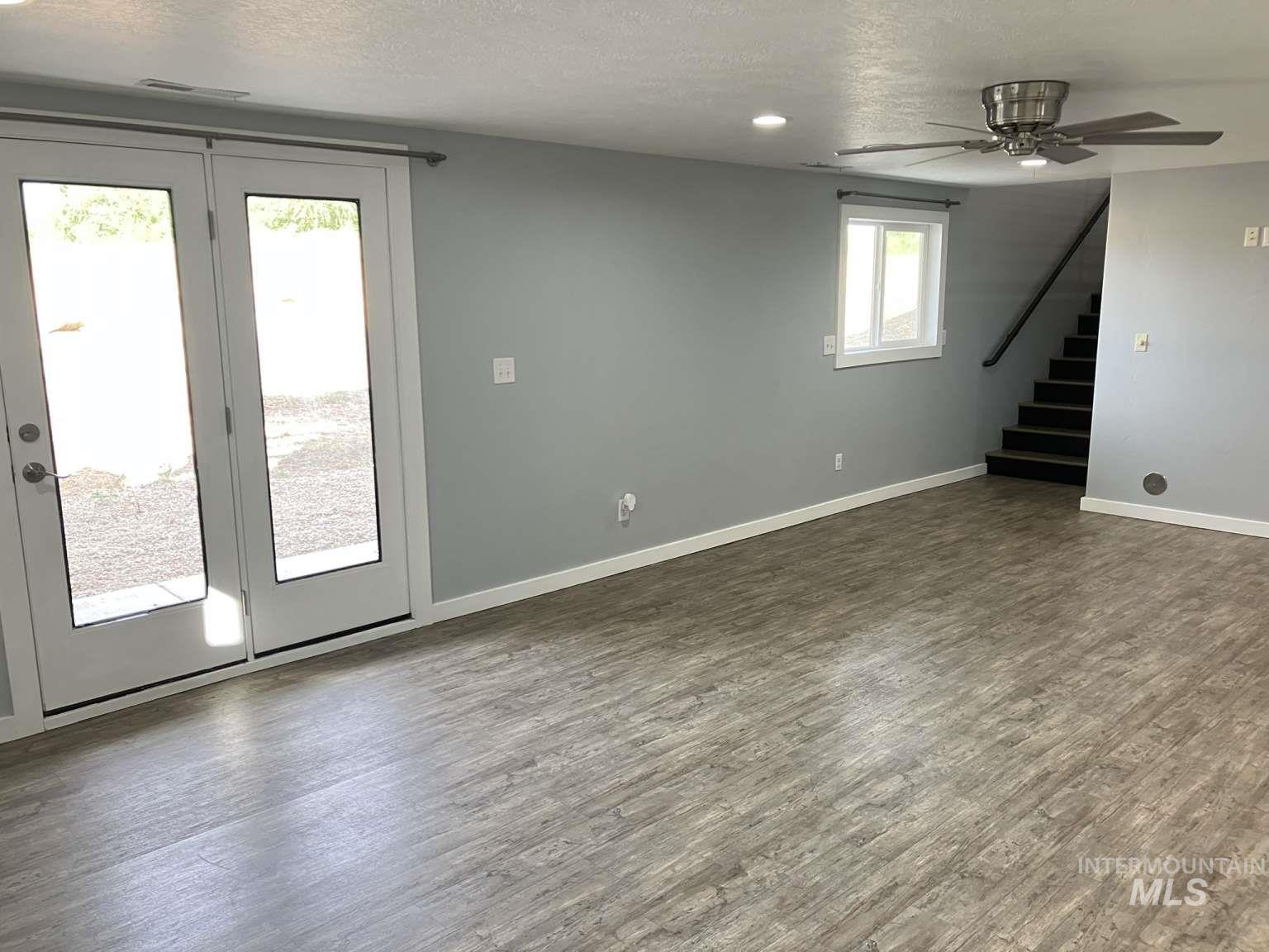 Basement featuring dark wood finished floors, a textured ceiling, a ceiling fan, and stairs