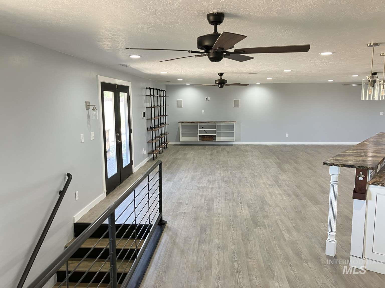 Unfurnished living room with a textured ceiling, recessed lighting, wood finished floors, and a ceiling fan