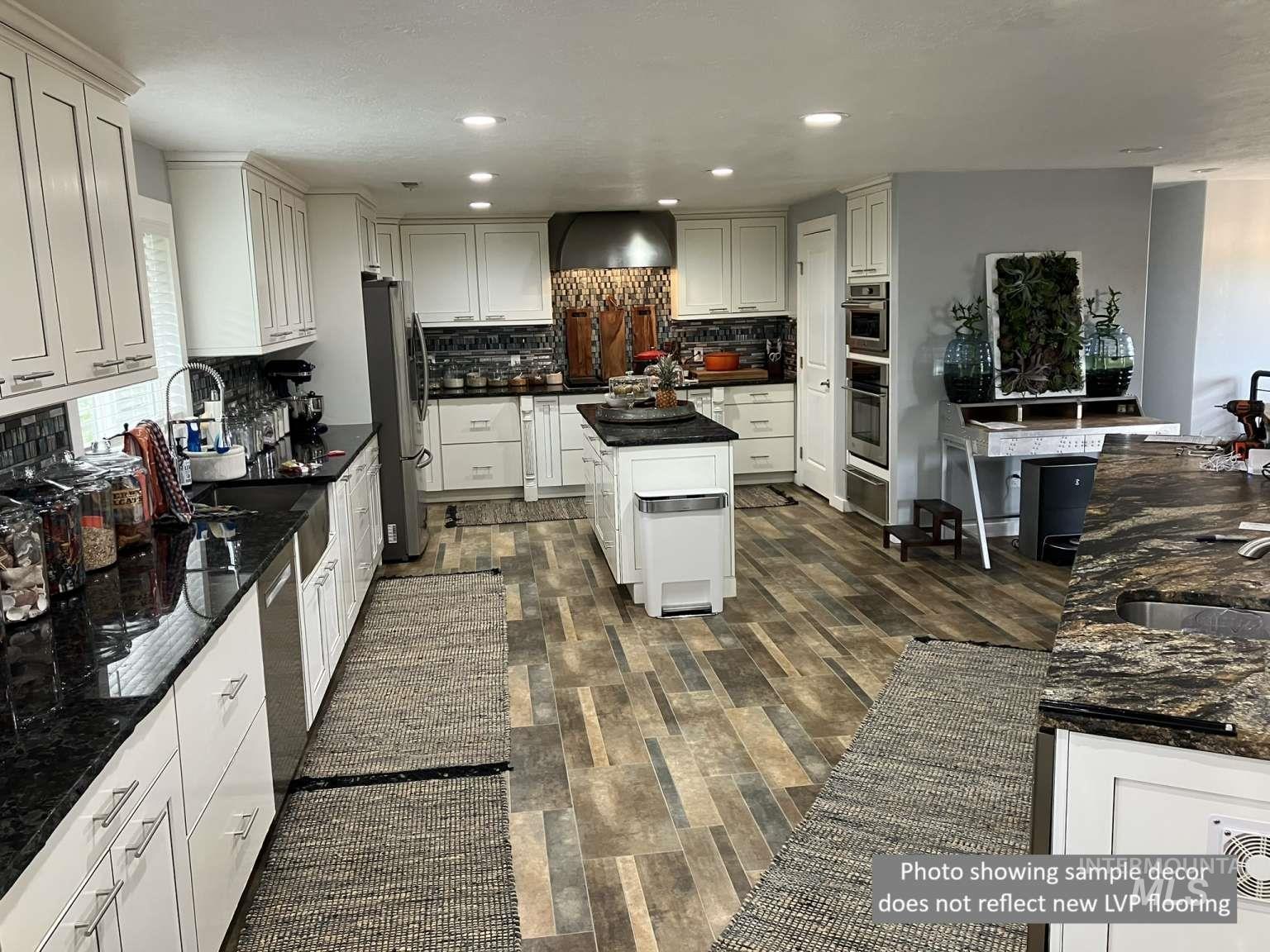 Kitchen with recessed lighting, dark countertops, tasteful backsplash, appliances with stainless steel finishes, and white cabinetry