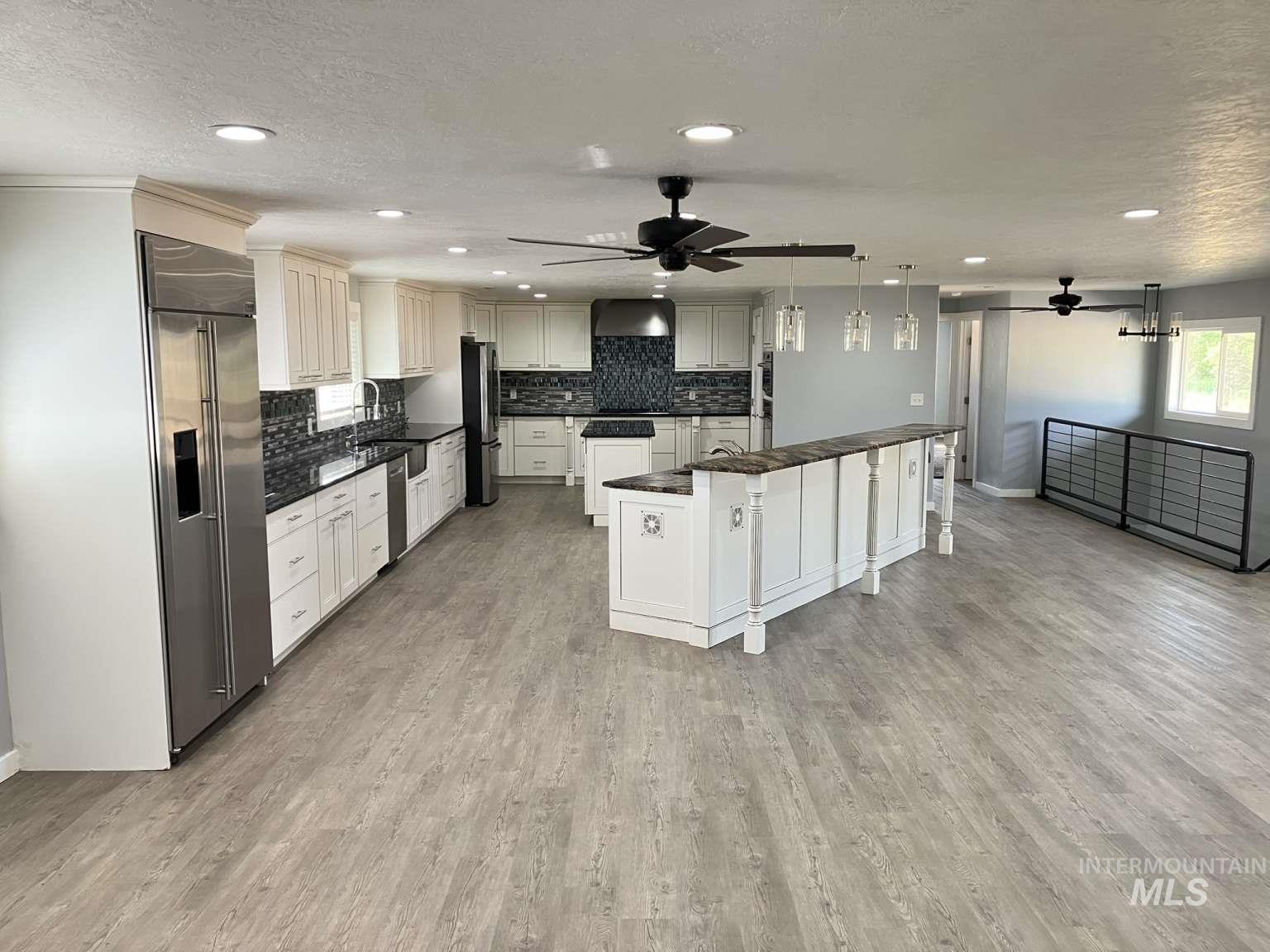Kitchen with dark countertops, stainless steel built in fridge, a center island, decorative backsplash, and a textured ceiling