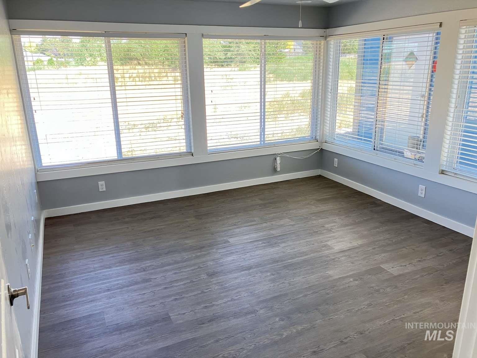Unfurnished sunroom featuring wood finished floors and baseboards