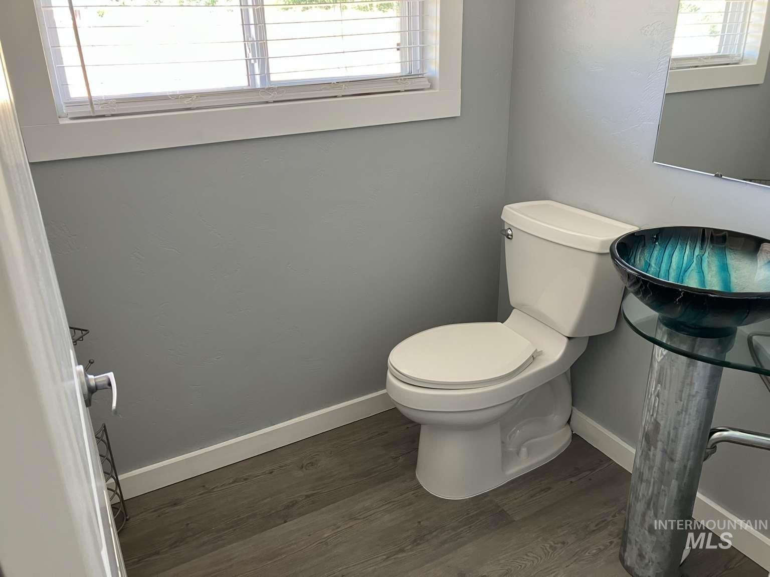 Half bathroom featuring toilet and wood finished floors