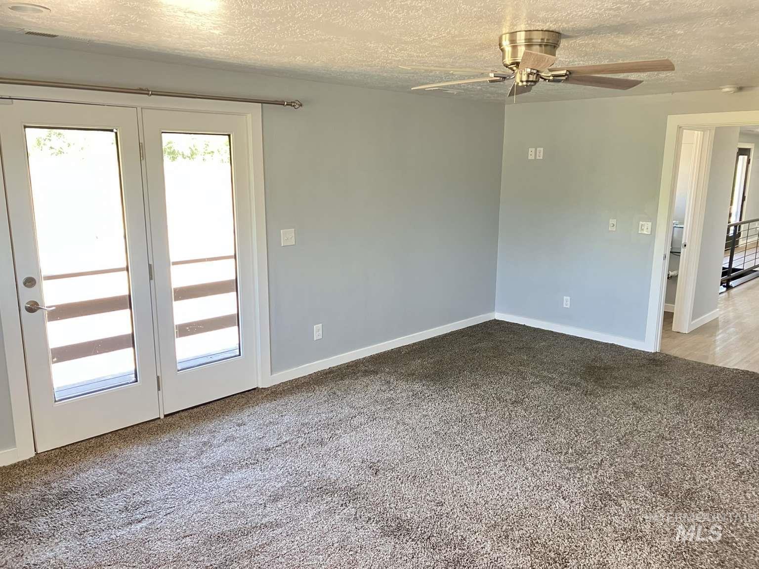 Empty room with a textured ceiling, carpet, and a ceiling fan