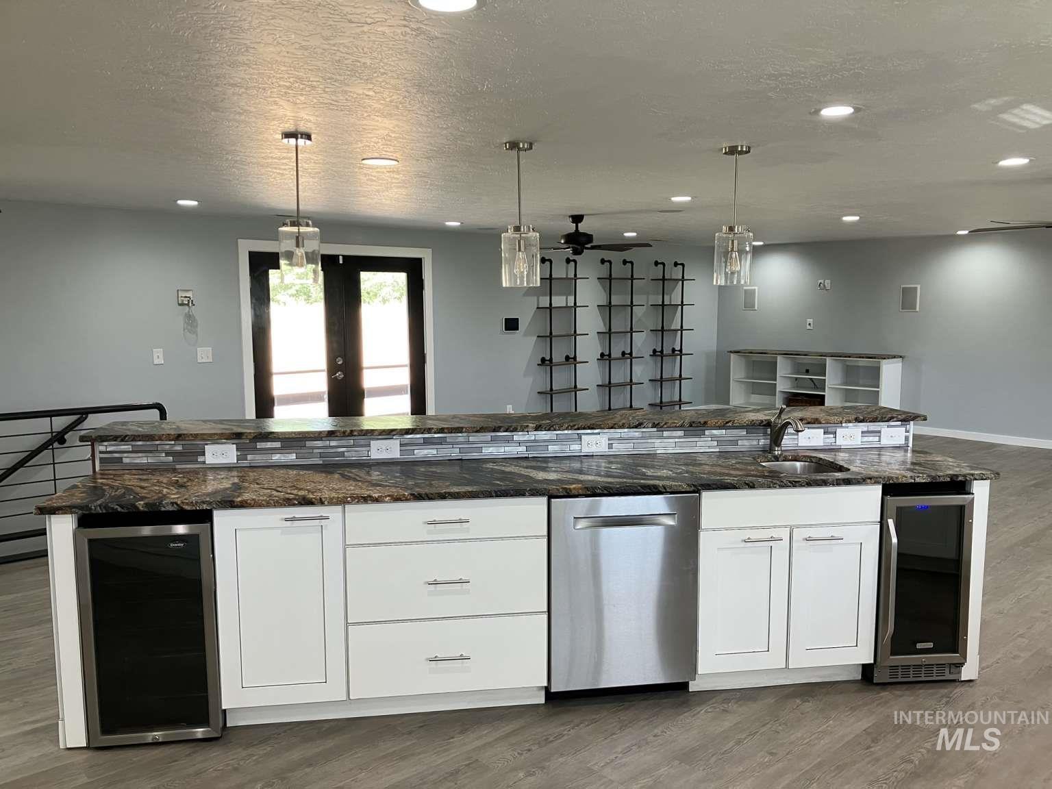 Kitchen featuring beverage cooler, stainless steel dishwasher, dark wood finished floors, a textured ceiling, and recessed lighting