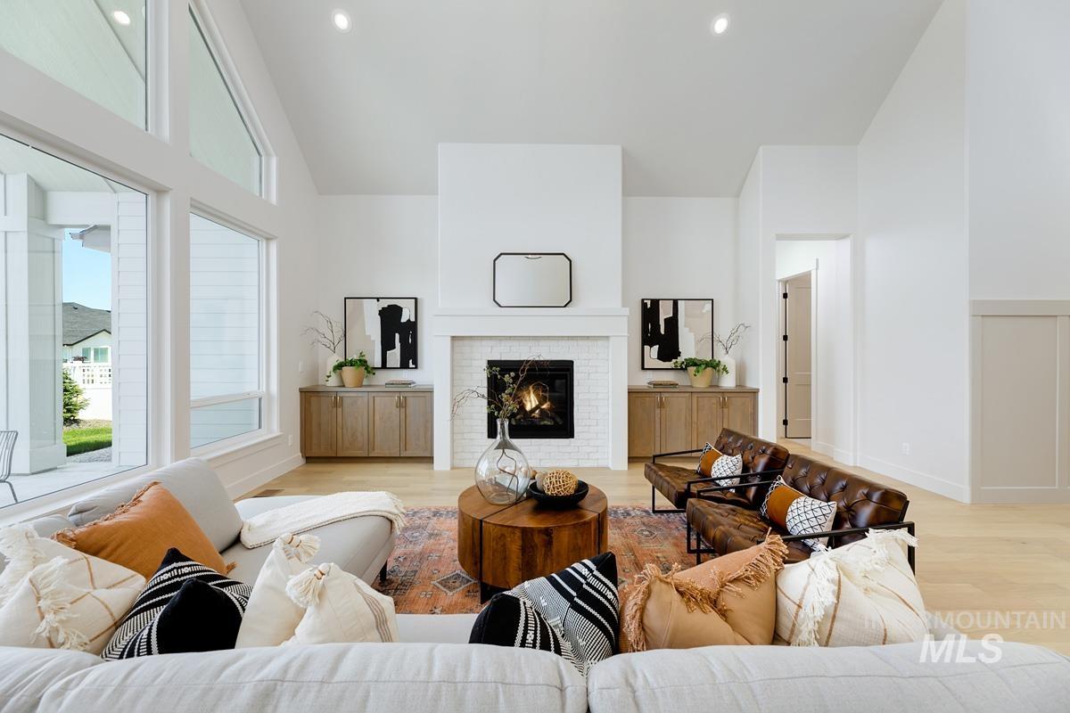 Living area featuring light wood-type flooring, a brick fireplace, vaulted ceiling, and recessed lighting