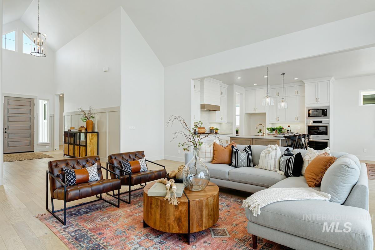 Living area with light wood-style flooring, a chandelier, and vaulted ceiling
