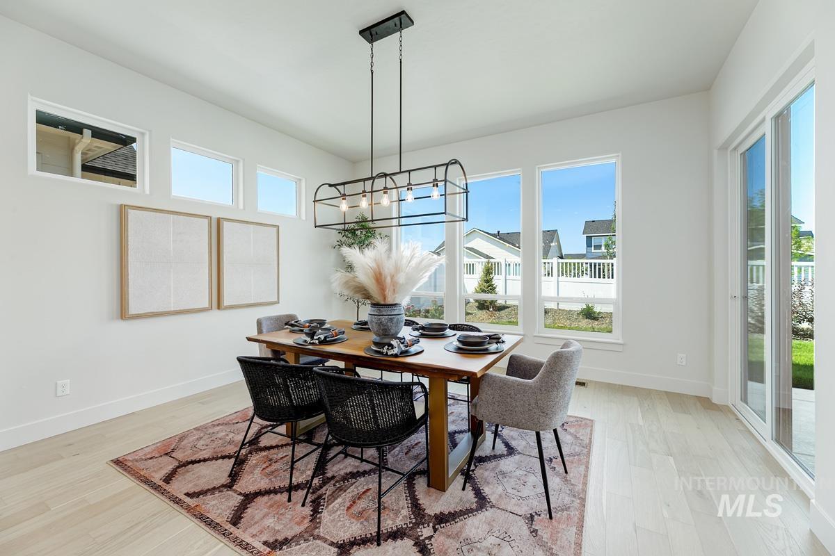Dining room with light wood-type flooring and suspended lighting