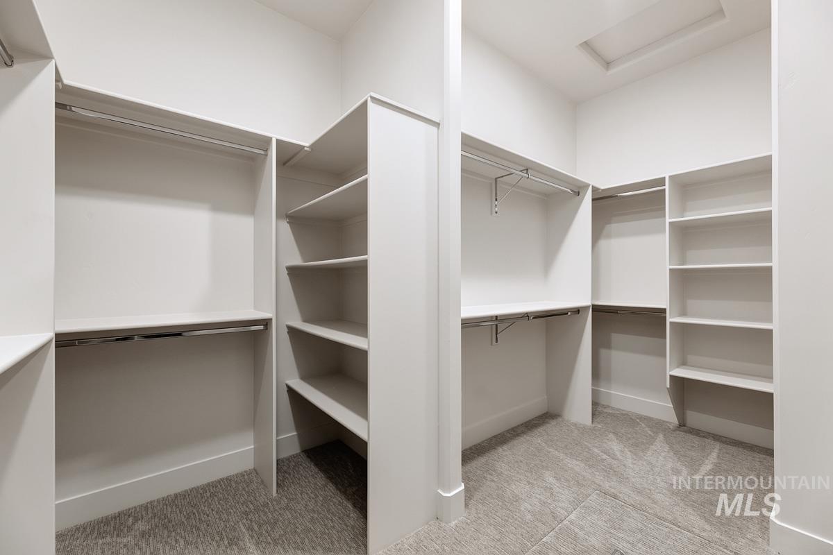 Walk in closet featuring attic access and light carpet