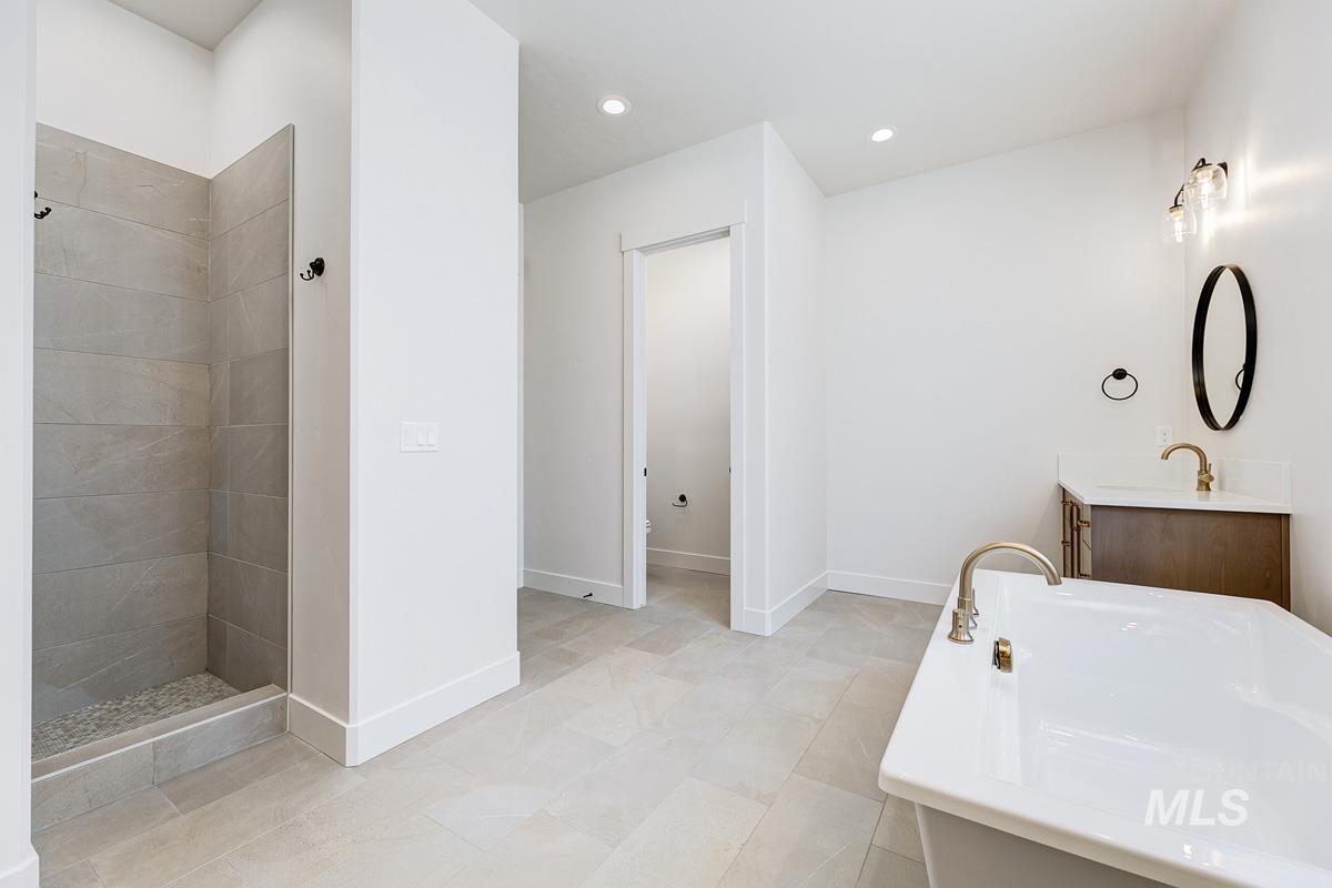 Bathroom featuring vanity, a soaking tub, tiled shower, and recessed lighting
