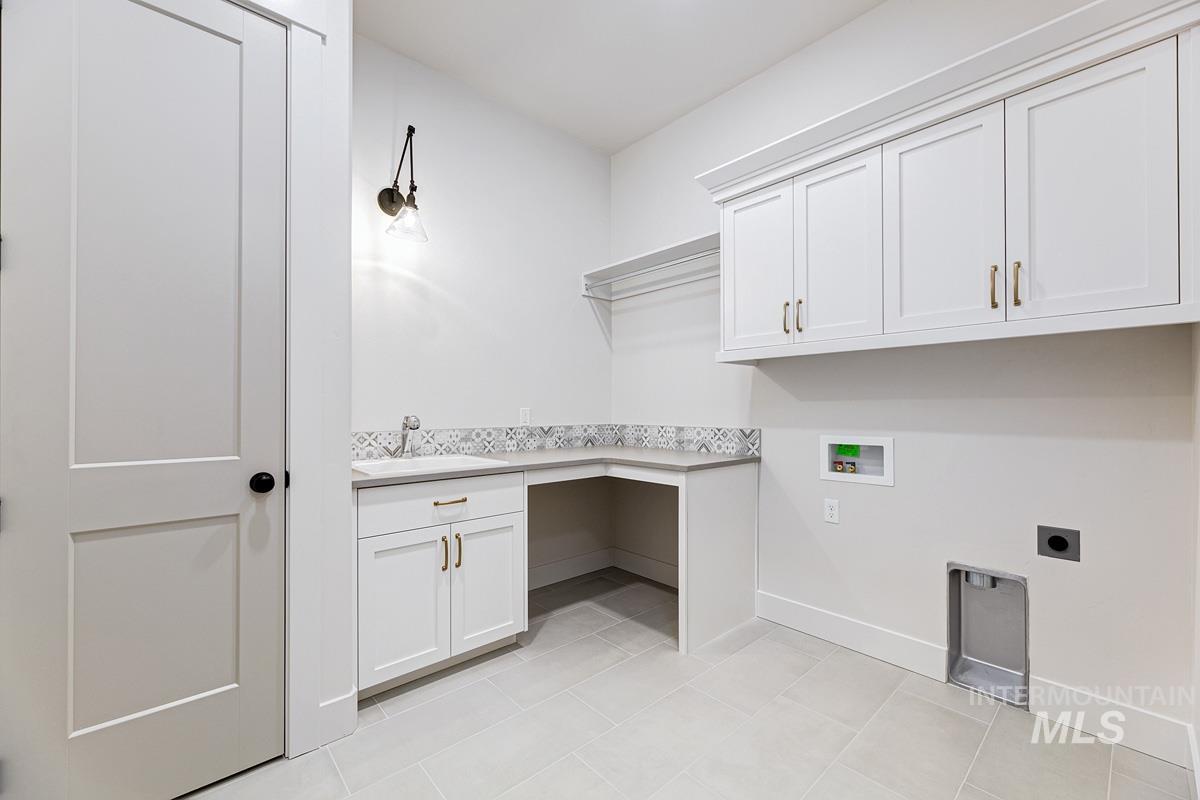 Laundry area with hookup for a washing machine, cabinet space, hookup for an electric dryer, and light tile patterned floors
