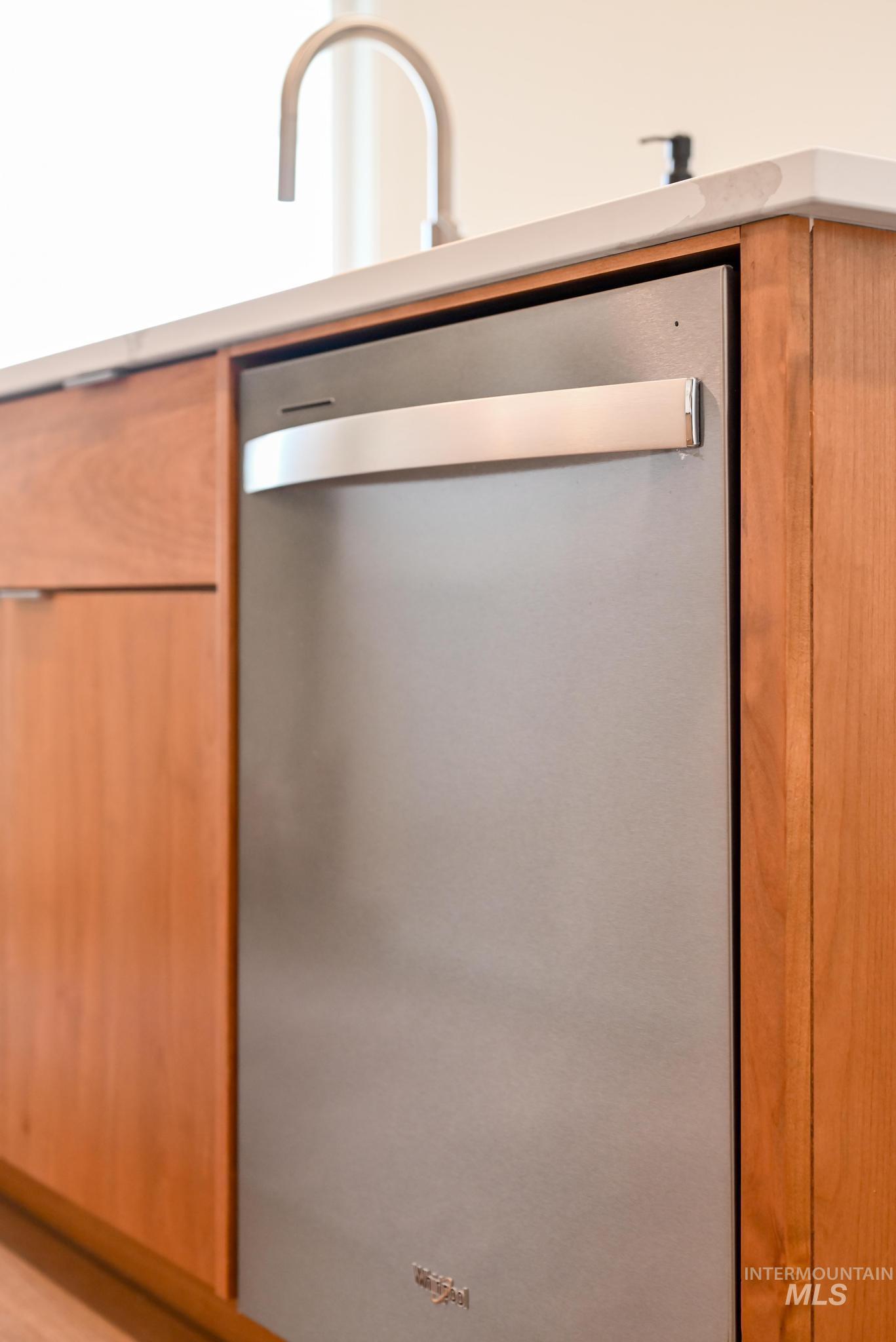 Kitchen view of stainless steel dishwasher, brown cabinets, and modern cabinets