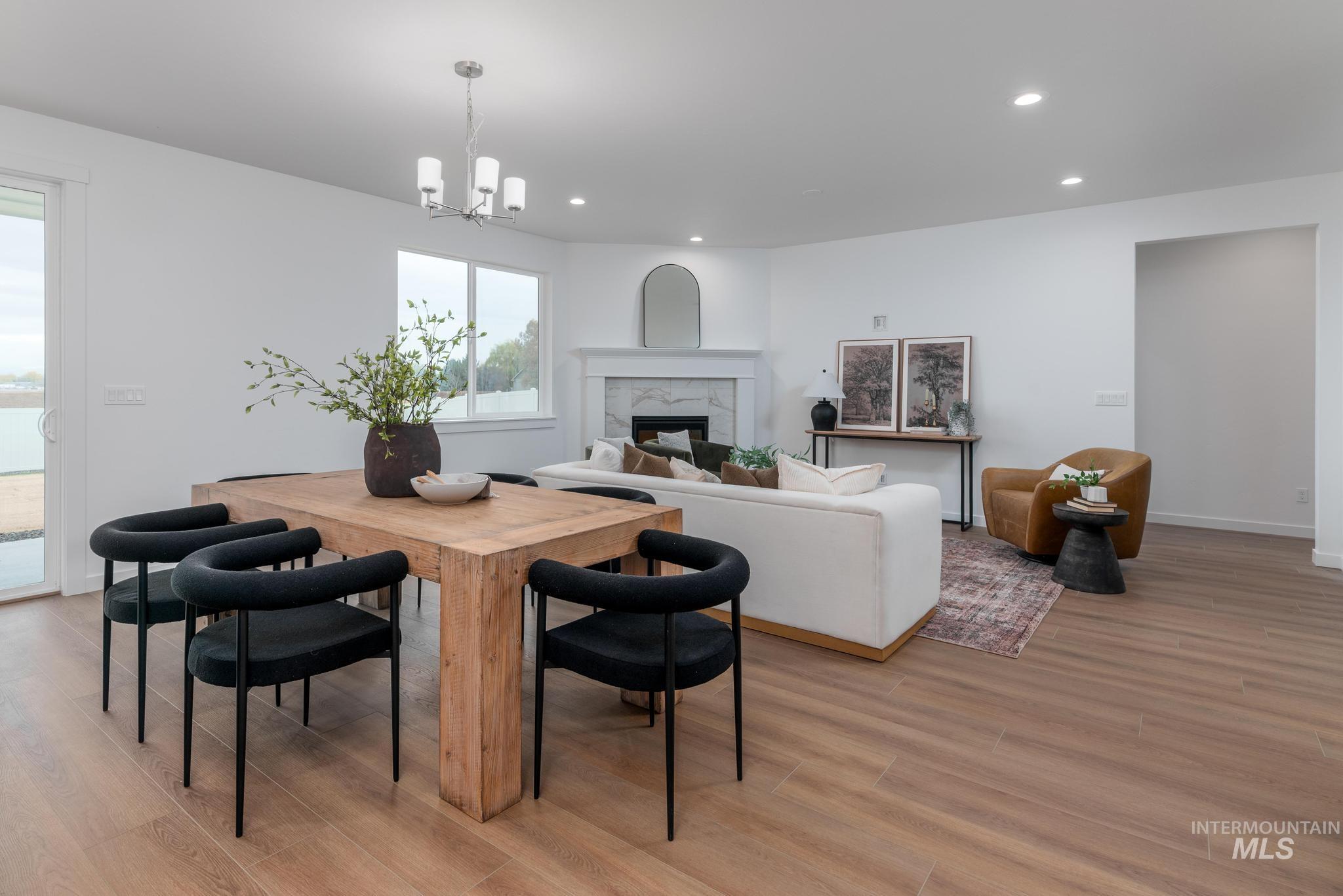 Dining room featuring recessed lighting, a premium fireplace, light wood finished floors, and a chandelier