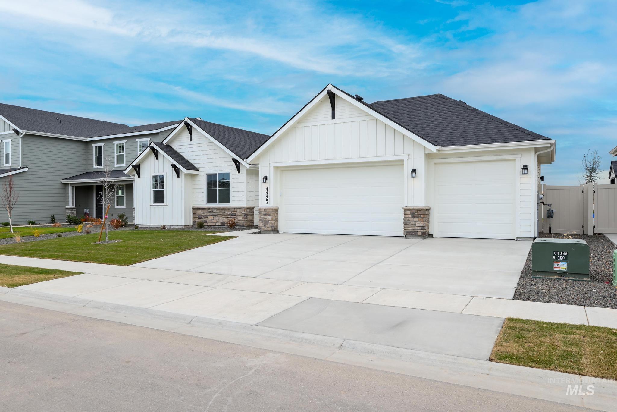 View of front facade featuring board and batten siding, driveway, roof with shingles, an attached garage, and stone siding