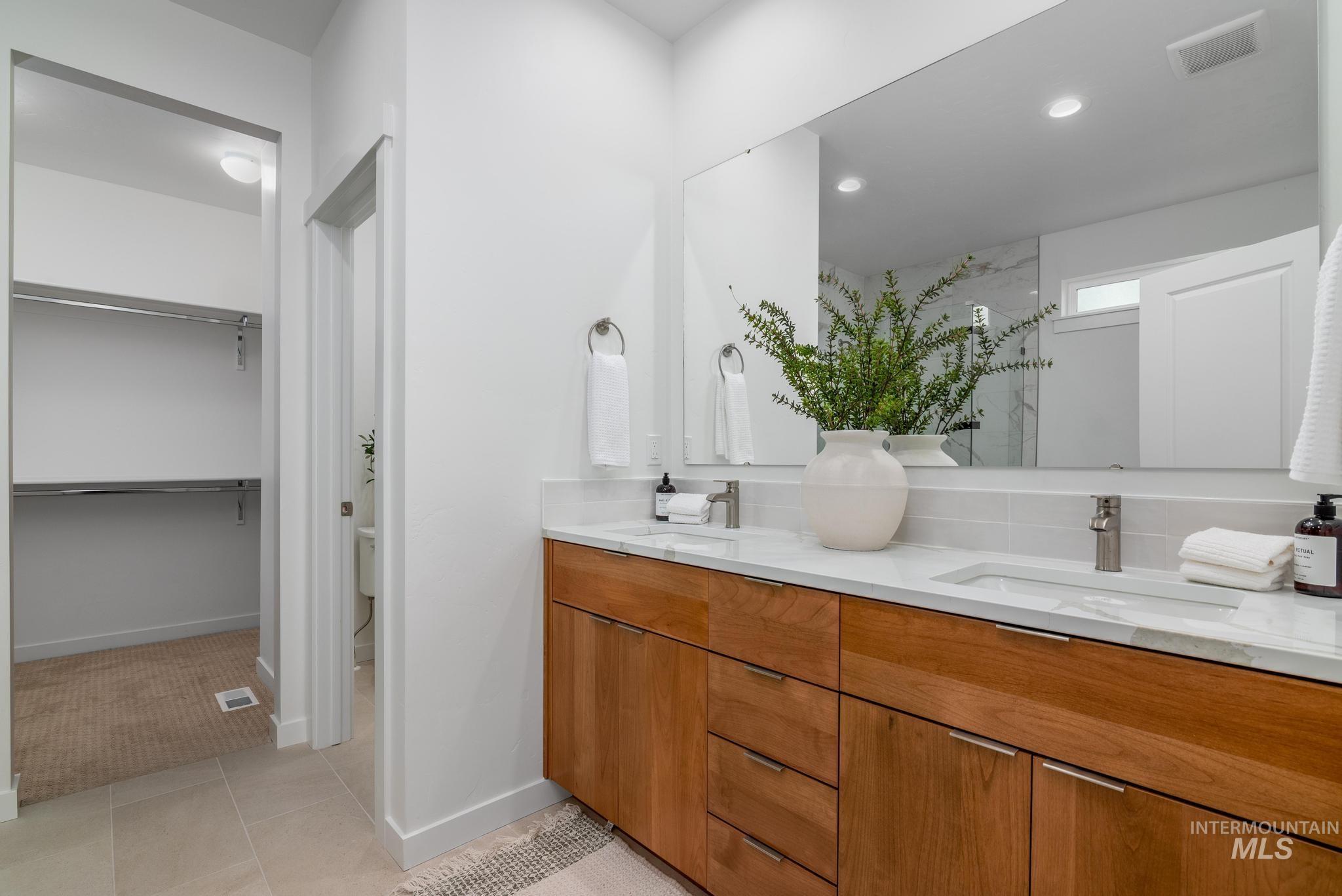 Bathroom with double vanity, a marble finish shower, light tile patterned floors, a spacious closet, and recessed lighting