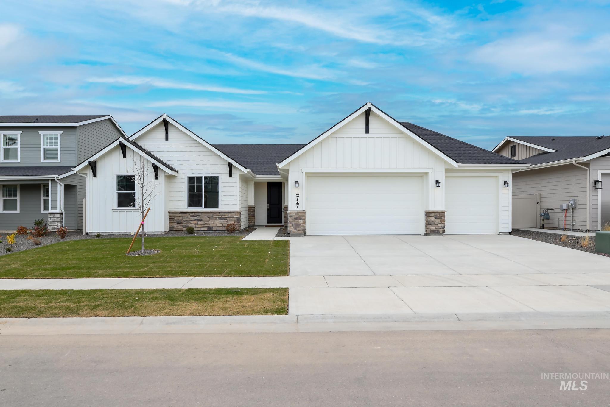 View of front of home featuring board and batten siding, stone siding, an attached garage, and concrete driveway