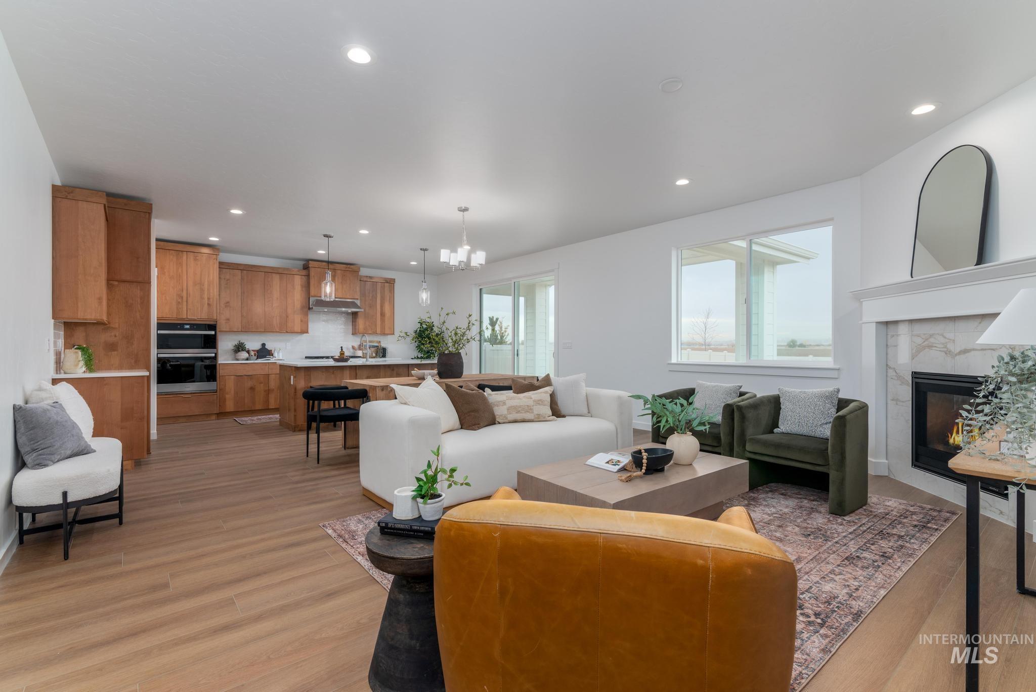 Living room featuring light wood finished floors, a chandelier, a fireplace, and recessed lighting