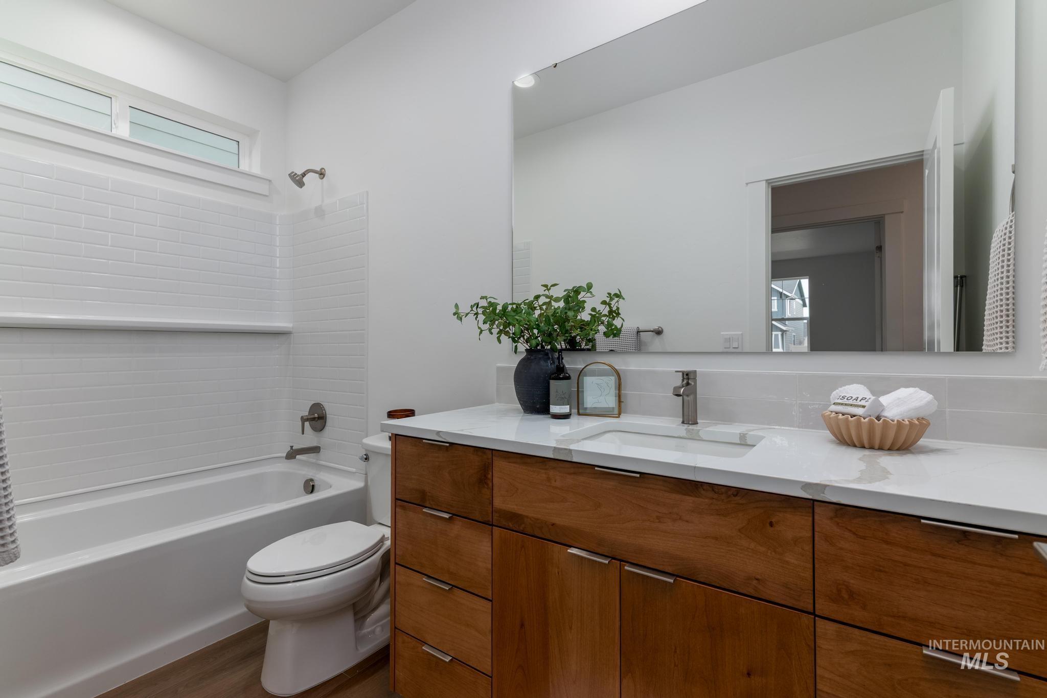 Bathroom with shower / bathtub combination, vanity, and dark wood-style floors