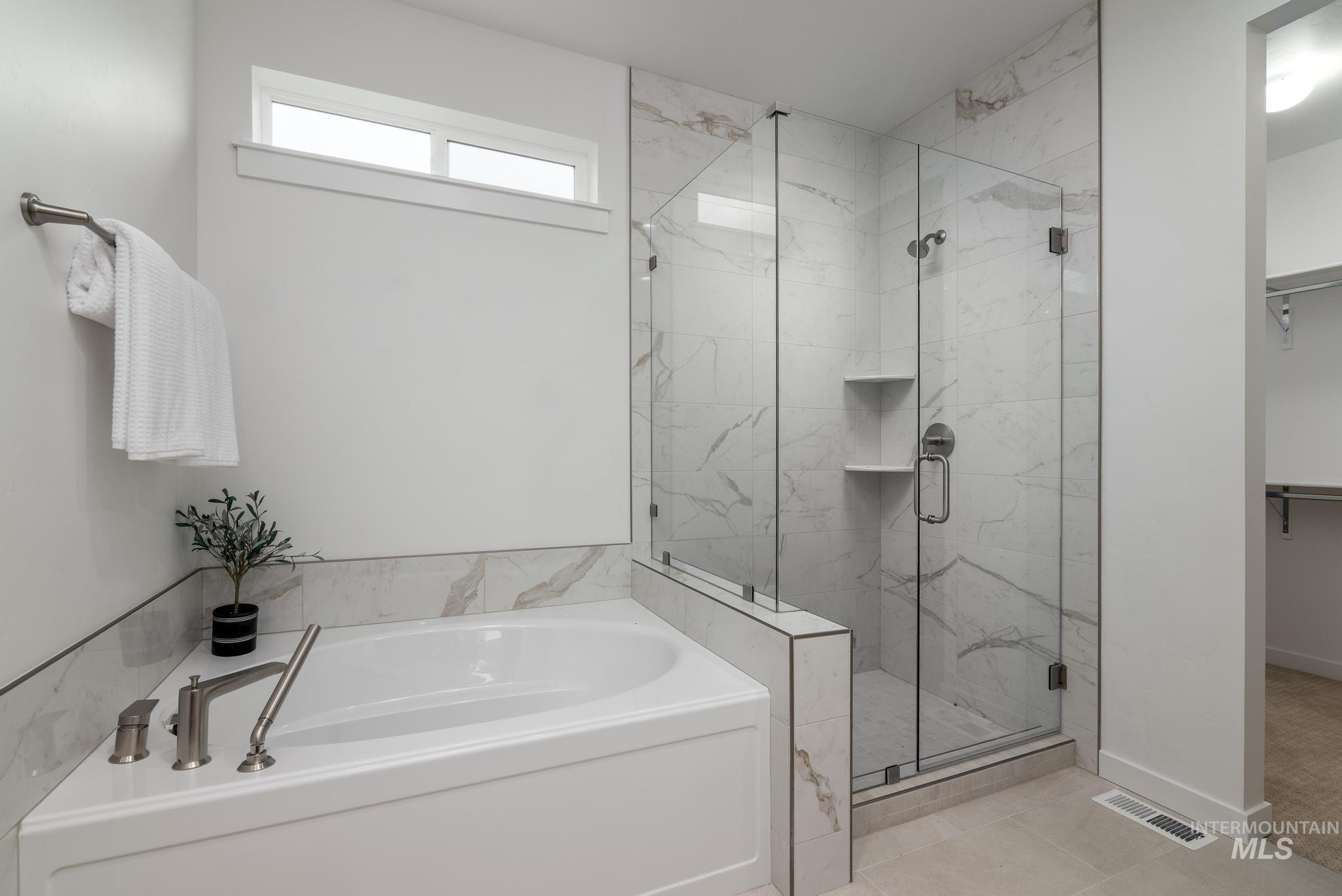 Full bath featuring a bath, a marble finish shower, tile patterned flooring, and a spacious closet