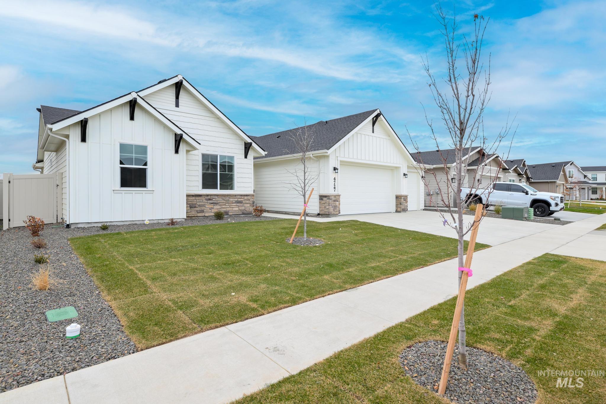 View of front of property with board and batten siding, concrete driveway, a garage, and stone siding