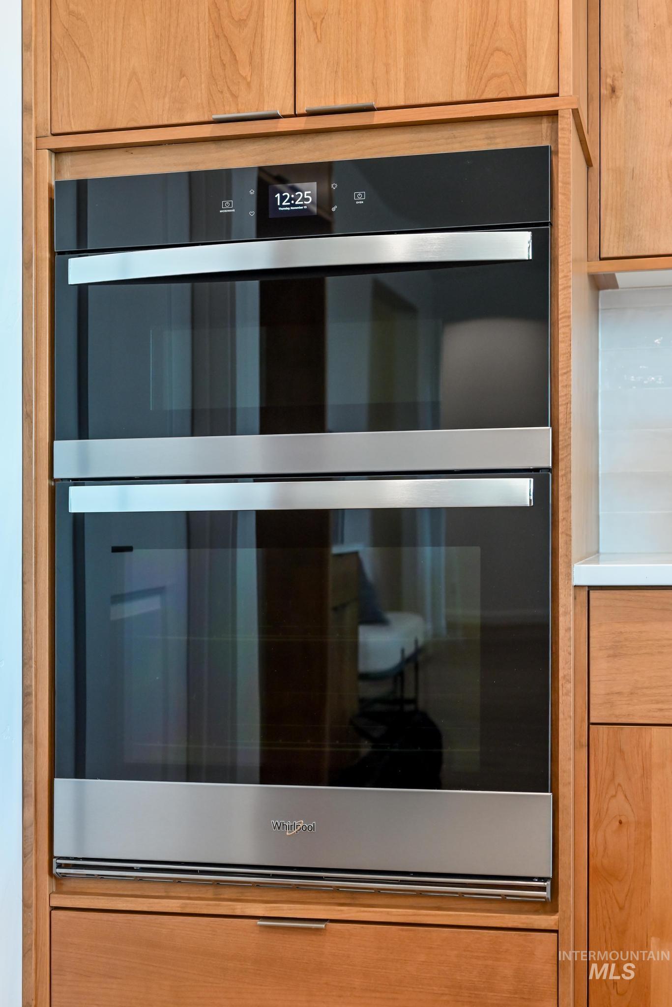Detailed view of double oven, light countertops, and light brown cabinetry