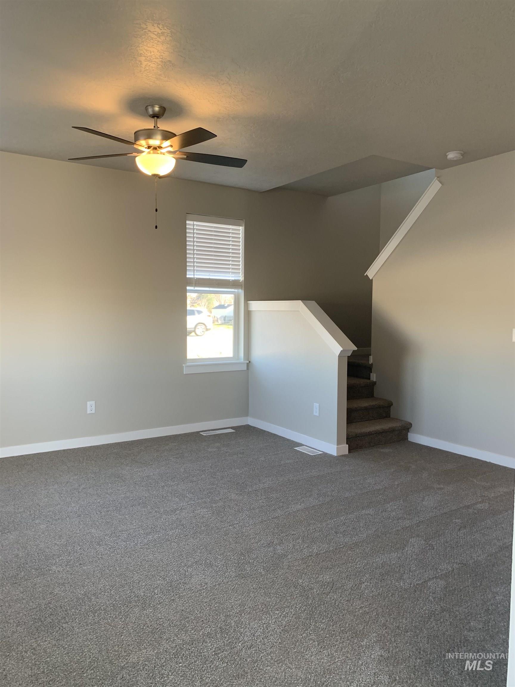 Unfurnished living room with carpet floors, a ceiling fan, and a textured ceiling